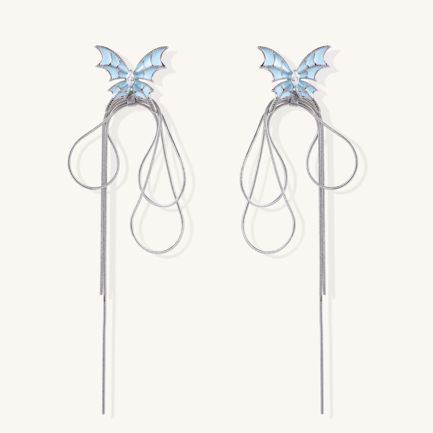 Blue enamel butterfly earrings with cascading gold-plated chains and zirconia crystal accents on white background.